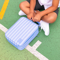 AMontii Splash Stripe Large Insulated Lunch Bag on a green outdoor court, with a child sitting nearby in a white shirt and dark shorts.