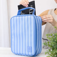 A Montii Splash Stripe Large Insulated Lunch Bag, shown being packed with the Montii best-selling ice pack by a person in a neutral indoor setting.