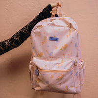 Fox & Fallow backpack with mermaid pattern held by a hand against a beige background