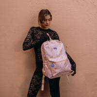 Women wearing a black lace outfit holding a Fox and Fallow backpack against a beige wall
