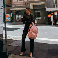 Woman holding a Fox & Fallow backpack and a coffee on a city street