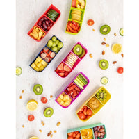 Montii Feast Silicone Trays filled with fruits and vegetables on a light surface.