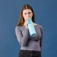 Woman holding a Lagoon BBox Stainless Steel water bottle against a blue background