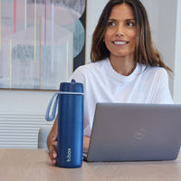 Woman holding a Midnight b.box water bottle in front of a laptop.