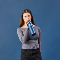 Woman holding a Midnight BBox Drink bottle against a blue background