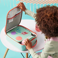 Child opening the BBox Little Mermaid Insulated Lunchbag filled with the BBox Lunchbox and Snackbox on a table against a turquoise background
