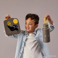 Child holding a BBox Batman-themed lunch box and water bottle against a plain background