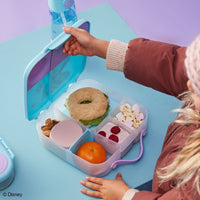 Child opening a Frozen BBox lunchbox with compartments containing a sandwich, fruit, and snacks on a blue surface.