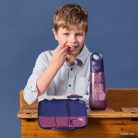 Child sitting at a desk with a BBox Harry Potter lunchbox and the Harry Potter water bottle on a blue background