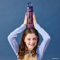 Girl holding the BBox Harry Potter water bottle with a blue background
