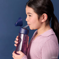 Person drinking from the BBox Harry Potter water bottle with a straw on a dark background