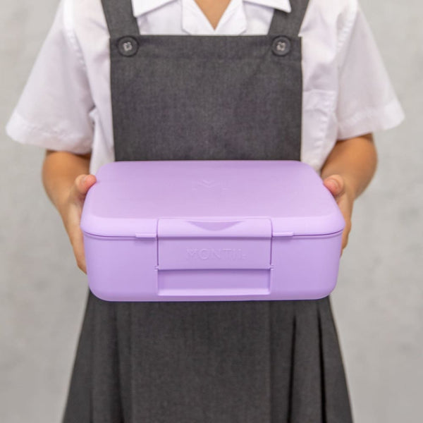 Child holding a Lilac Montii Feast lunchbox against a plain background